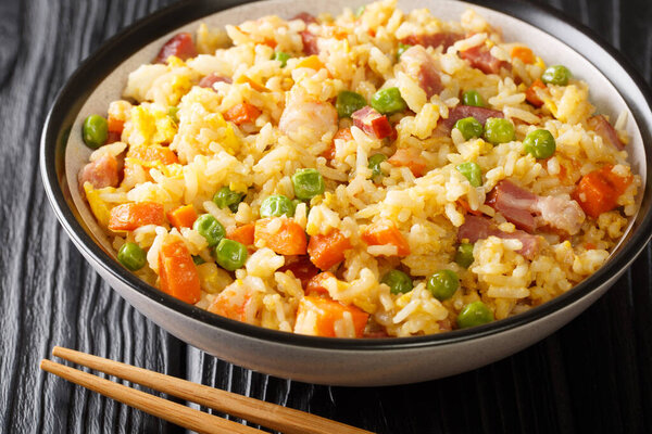 Янчжоу жареный рис является китайское блюдо, состоящее из риса, яйца и овощей, таких как морковь, горох, а также креветки, мясо близко в тарелке на столе. Фалонта
