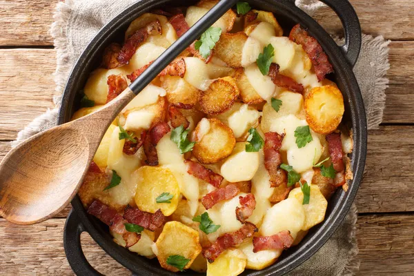 Truffade Potato Cake with Cheese and Bacon Recipe close up in the pan on the table. Horizontal top view from abov