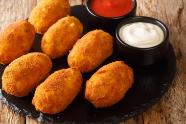 İspanyol kroketleri ve tuzlu morina sosu masaya yakın plan bir tabakta servis edilir. yatay
