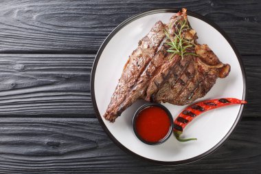 Biberiyeli ve baharatlı biftek ve biftek siyah masanın üzerindeki tabakta kapatılıyor. Yukarıdan yatay üst görünüm