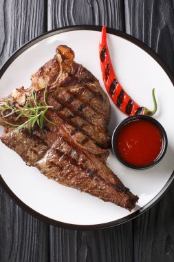 Domates soslu ızgara biftek ve ahşap bir masada yakın plan kırmızı biber. yukarıdan dikey üst görünüm