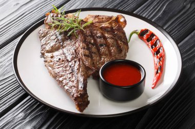 Biberiyeli ve baharatlı biftek ve biftek siyah masanın üzerindeki tabakta kapatılıyor. Yatay