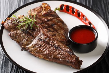 Siyah masadaki tabakta taze biberiyeli ızgara barbekü T-Bone bifteği. Yatay