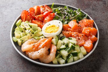 Somon, karides, yumurta ve taze sebzelerin kahvaltısı için keto diyet porsiyonu beton bir masada yakın plan bir tabakta. yatay