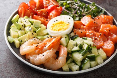 Somon, karides, yumurta ve taze sebzelerden oluşan organik kahvaltı beton bir masada yakın plan bir tabakta. yatay