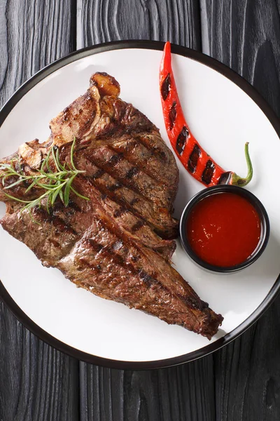 Domates soslu ızgara biftek ve ahşap bir masada yakın plan kırmızı biber. yukarıdan dikey üst görünüm