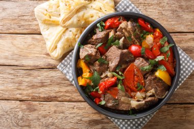 Lezzetli bugma eti. Sebze ve otlarla pişirilmiş. Tahta bir masada, kendi meyve suyunun içinde. Yukarıdan yatay üst görünüm