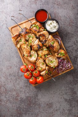 Appetizer chicken kebab with vegetables closeup on wooden board close-up. Vertical top view from abov
