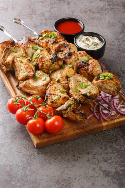 Appetizer chicken kebab with vegetables closeup on wooden board close-up. Vertica