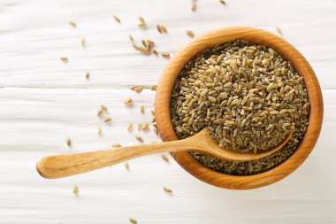 Organik Çiğ Buğday Kırığı Freekah beyaz kırsal masada tahta kaşıkla bir kasede. Yukarıdan yatay üst görünüm