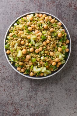 Masadaki tabakta nohut, kereviz ve otlarla vejetaryen freekeh salatası. Yukarıdan dikey üst görünüm