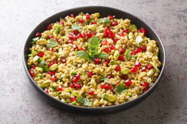 Sehpadaki tabakta nar, fındık ve otlarla nefis vejetaryen freekeh. yatay