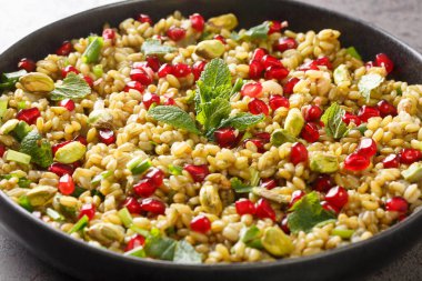 Nar, fındık ve otlarla kaynatılmış freekeh masadaki tabakta. yatay