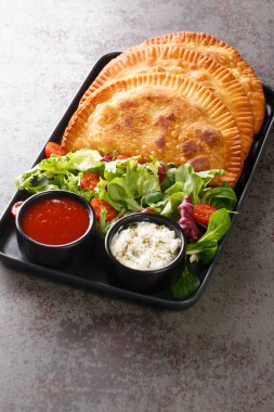 Geleneksel Rus usulü yağda kızartılmış etli turta chebureki taze salata ve soslar masanın üstünde. Dikey