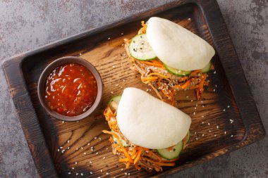 Bao dürümünde domuz eti, masanın üzerindeki tahta tahtada sosla servis ediliyor. Yukarıdan yatay üst görünüm