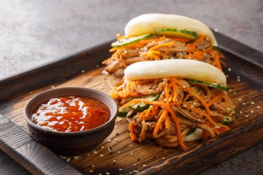 Bao dürümünde domuz eti, masanın üzerindeki tahta tahtada sosla servis ediliyor. Yatay