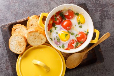 Domates, maydanoz, et ve peynirle pişirilmiş yumurta masadaki ahşap tepside. Yukarıdan yatay üst görünüm