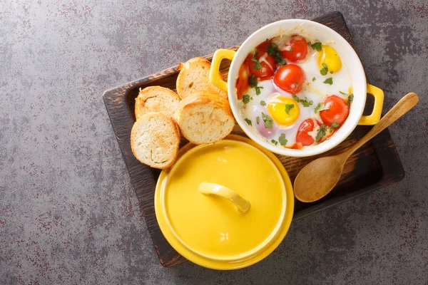 Krem peynirli yumurta ve sıcak tostla servis edilen Cocotte yumurtaları masadaki ahşap tepsiye yakın çekim için. Yukarıdan yatay üst görünüm