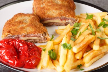 Cachopo, peynirle doldurulmuş iki dana fileto ve masanın üzerindeki beyaz tabakta yakın plan patates kızartması ile Serrano jambonu içerir. Yatay