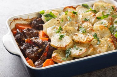 Lancashire Hot Pot, üzerinde dilimlenmiş patates ve fırın bulunan kuzu ve sebzeler masanın üzerindeki fırında yakın plan. Yatay