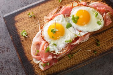 Kavrulmuş jambonlu sandviç ve masanın üzerindeki tahta tahtaya yakın plan yumurta. Yukarıdan yatay üst görünüm