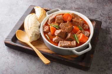 Slowly stewed spicy beef in red wine with vegetables closeup in the wooden tray on the table. Horizonta
