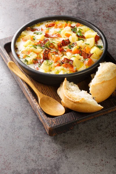 Geleneksel domuz pastırmalı Polonya Patates Çorbası. Tahta tepsinin üzerindeki kaseye yakın plan. Dikey