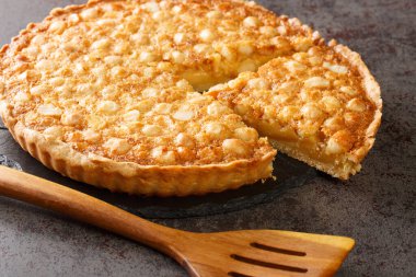 Caramel macadamia tart baked in a buttery homemade shortcrust pastry closeup in the board on the table. Horizonta