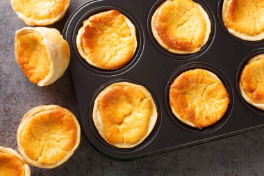 Queijada 's Portuguese Custard Cupcakes' i masadaki fırın tabağında yakın plan çekimde. Yukarıdan yatay üst görünüm