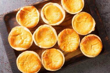 Portekiz peynirli tarts Queijadas masadaki ahşap tepside duran tatlı, kremalı, geleneksel bir tatlıdır. Yukarıdan yatay üst görünüm