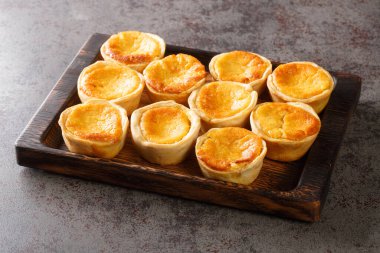 Lezzetli Portekiz Mini Tarts Queijadas masadaki ahşap tepside duran tatlı, kremalı, geleneksel bir tatlıdır. Yatay
