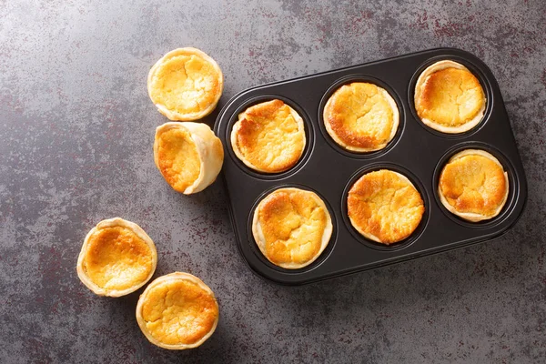 Queijadas ya da Queijadinhas, küçük Portekiz peynirli kekleri Queijo Fresco 'nun yakın planında masanın üstünde. Yukarıdan yatay üst görünüm