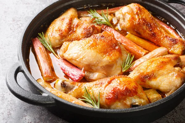 stock image Delicious chicken braised and then baked with rhubarb, rosemary and white wine close-up in a frying pan on the table. horizonta