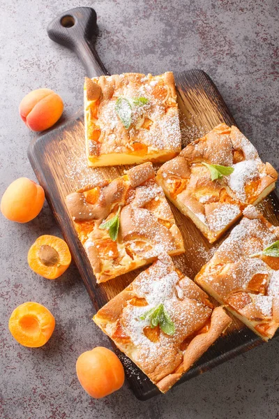 Kayısılı sünger kek, masanın üzerindeki tahta tahtaya yakın plan şekerle kaplanmış. Yukarıdan dikey üst görünüm