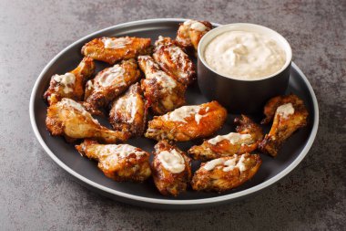 Masadaki tabakta Alabama beyaz barbekü soslu ızgara tavuk kanadı. Yatay