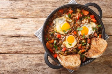 Acquacotta Maremmana yumurtalı sebze çorbası. Masadaki tencerede yakın plan ev yapımı ekmekle servis ediliyor. Yukarıdan yatay üst görünüm