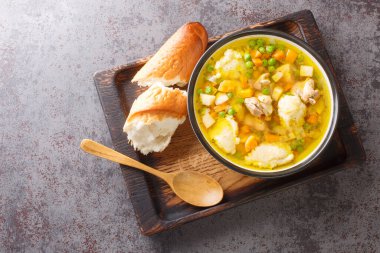 Ev yapımı havuç, soğan, kereviz kökü, maydanoz ve irmik köfteli tavuk çorbası masanın üstünde. Yukarıdan yatay üst görünüm