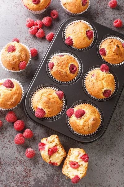 stock image Summer raspberry muffins with white chocolate close-up in a muffin pan on the table. Vertical top view from abov