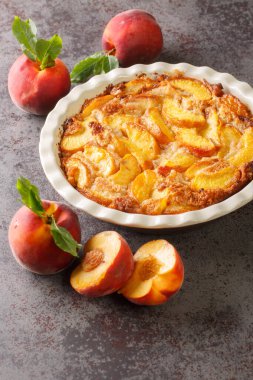 Ev yapımı şeftali turtası, beton gri arka planda pişirme kabında ufalanır. Dikey
