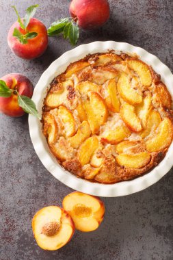 Taze organik şeftali ve masada seramik bir tabakta pişirilmiş lezzetli şeftalili tart. Yukarıdan dikey üst görünüm