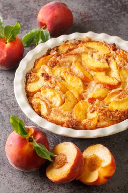 Taze organik şeftali ve masada seramik bir tabakta pişirilmiş lezzetli şeftalili tart. Dikey