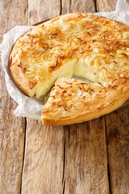 Argentinian Pizza Fugazzeta stuffed with cheese, and topped with the same sweet onions closeup in the plate on the wooden table. Vertica