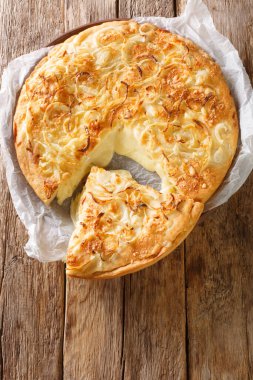 Fugazzeta or fugazza con queso a classic pizza is made with double cream cheese, mozzarella cheese, onion and olive oil closeup in the plate on the wooden table. Vertical top view from abov