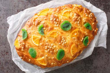 Traditional Spanish Catalan coca de Sant Joan with pine nuts, candied fruit closeup on the paper on the table. Horizontal top view from abov