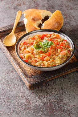 Eggplant caviar with tomatoes, garlic and roasted bell pepper closeup in the bowl on the table. Vertica
