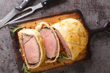 Beef Wellington classic steak dish closeup on rustic wooden board. Horizontal top view from abov