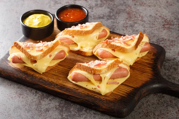 Sandwiches with egg, sausages and toast cheese fried in a pan closeup in the wooden board on the table. Horizonta