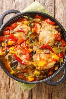 Kedjenou Chicken Ivory Coast Stew with vegetables in own juice closeup in the plate on the table. Vertical top view from abov