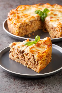 Köfteli spagetti turtası, peynir, domates sosu masanın üzerindeki tabağa yakın. Dikey