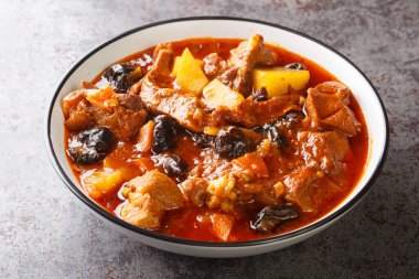 Khoresht Aloo Kuru erik ya da kuru erikli kuzu eti, domates, soğan, patates, havuç ve sarımsak masadaki kaseye yakın. Yatay